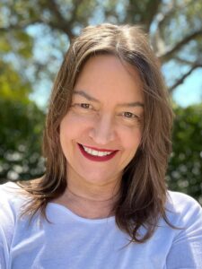 Felisa Strickland has shoulder length brown hair, wearing a white shirt outdoors